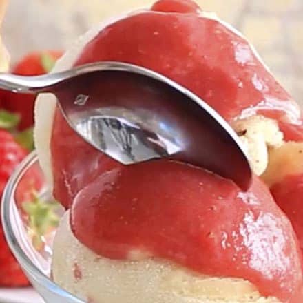 banana ice cream with strawberry sauce in a bowl with spoon