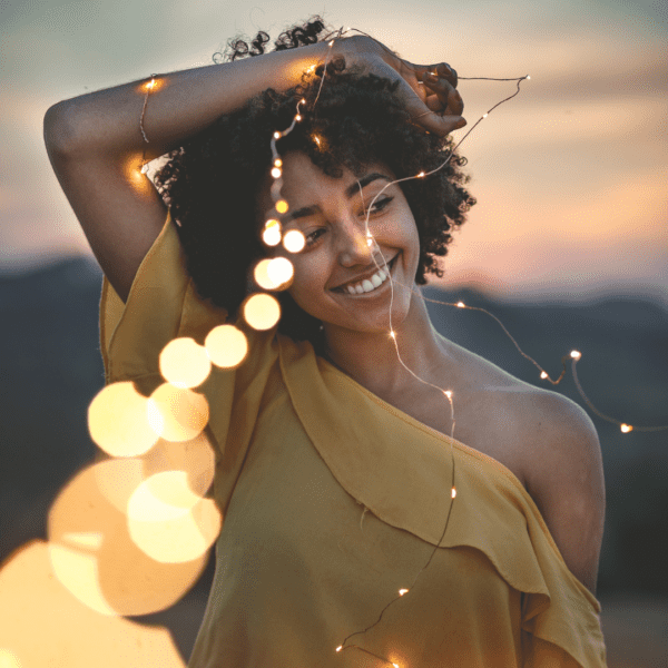 smiling woman with a string of lights