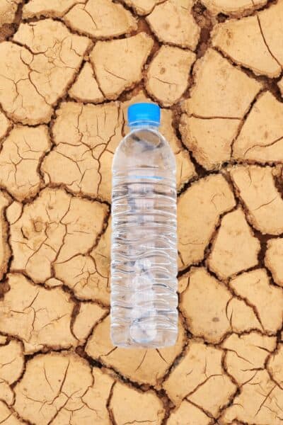 A water bottle on dry and cracked ground
