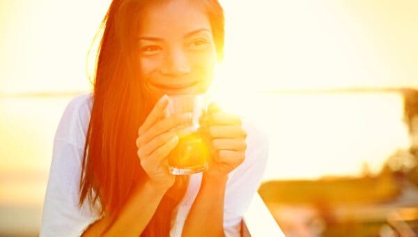 Asian woman drinking coffee in sun