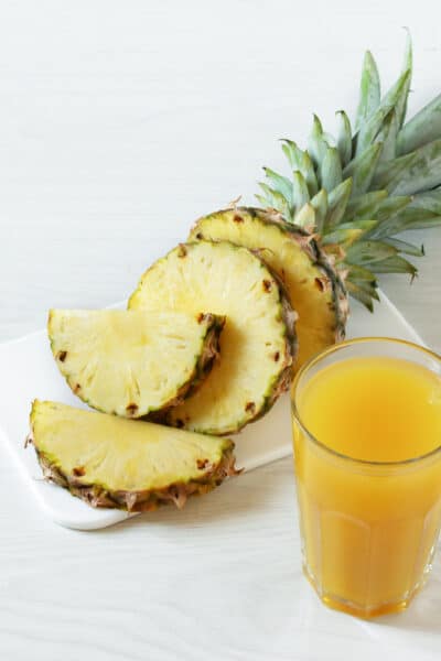Pineapple fresh juice in glass on white wooden table