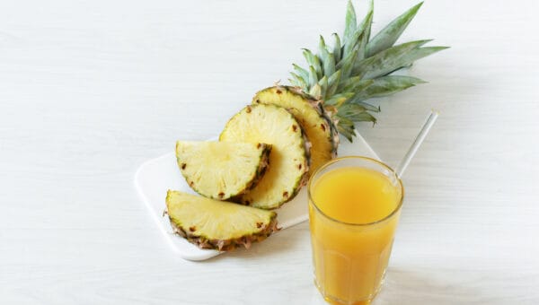 Pineapple fresh juice in glass on white wooden table